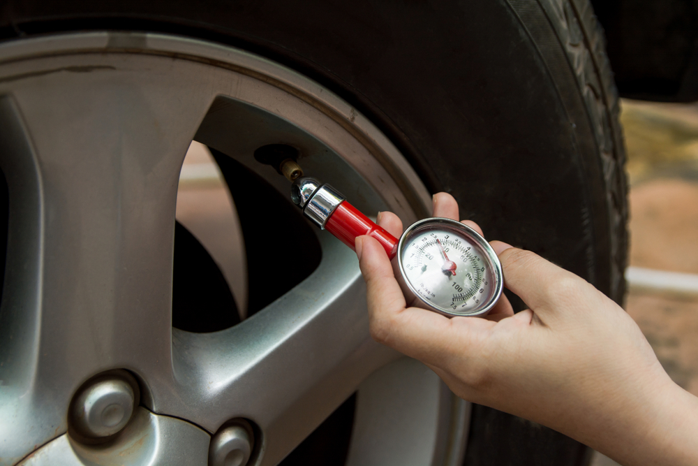 Image of a person checking tyre pressure with a tyre pressure gauge.