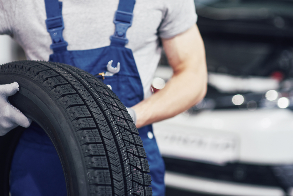 Photo of a mechanic holding a tyre, representing tyre fitting services.