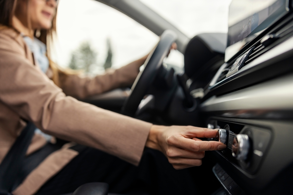 Photo of a woman in a car turning on the air conditioning.