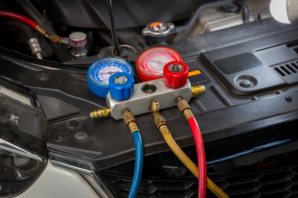 Photo of a car receiving an air conditioning service at a body shop.