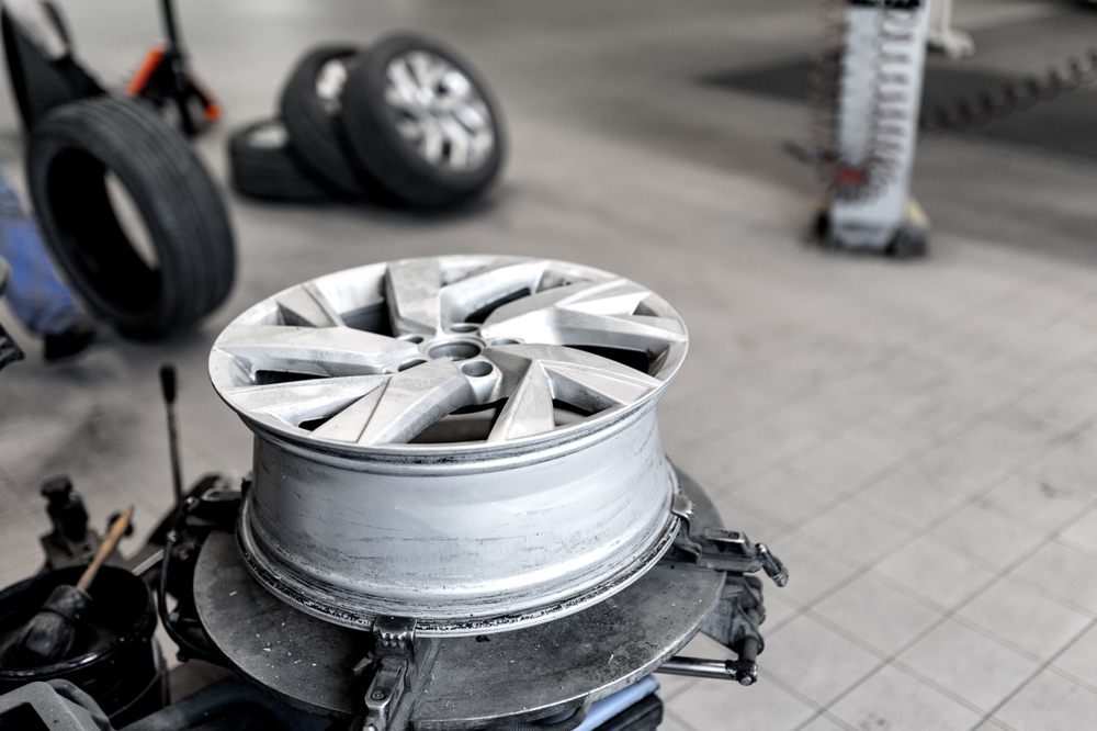 A silver alloy wheel rim in the foreground of a garage workshop.